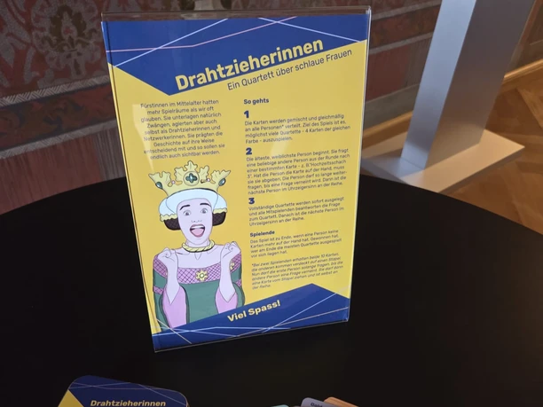 "Systemrelevant – Fürstinnen des Mittelalters" in Meißen Spielkarten-Set mit Frauengeschichten im historischen Raum auf schwarzem Tisch.