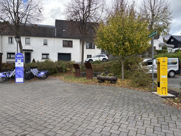 Radservice-Station Ruppichteroth Gelbe ADAC-Radservice-Station, umgeben von Fahrrädern und einem Baum mit herbstlichen Blättern.