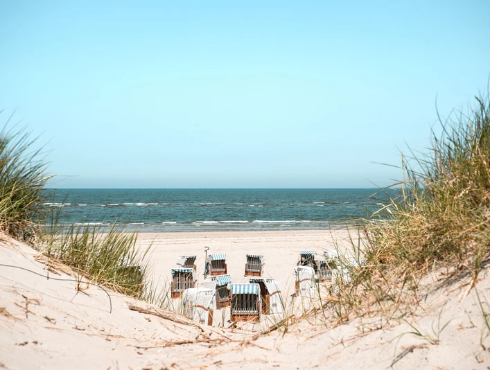 Spiekeroog_Strand_Dünen_Strandkörbe_Sommer_KL_2023.jpg Sanddünen mit Gräsern und Strandkörben am weiten Nordseestrand von Spiekeroog im Sommer