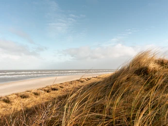 Dünen und Strand auf Spiekeroog Sandstrand mit Dünen und Meer auf Spiekeroog unter blauem Himmel mit leichter Bewölkung.