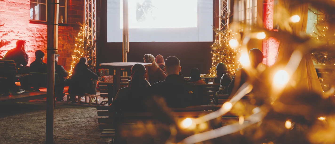 Filmhof - Rathausinnenhof Besucher sehen einen Film im festlich beleuchteten Rathausinnenhof.