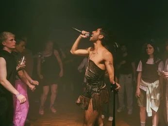 Bonanza festival Ein Performer singt leidenschaftlich inmitten eines nahen, hypnotisierten Publikums auf einer Party.A performer sings passionately in the midst of a close, mesmerized audience at a party.