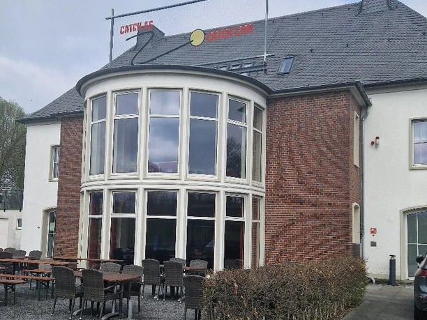 BottropMaschinenhausBernePark.jpg Backsteinbau mit großer Fensterfront und Außenterrasse mit Tischen und Stühlen im BernePark Bottrop