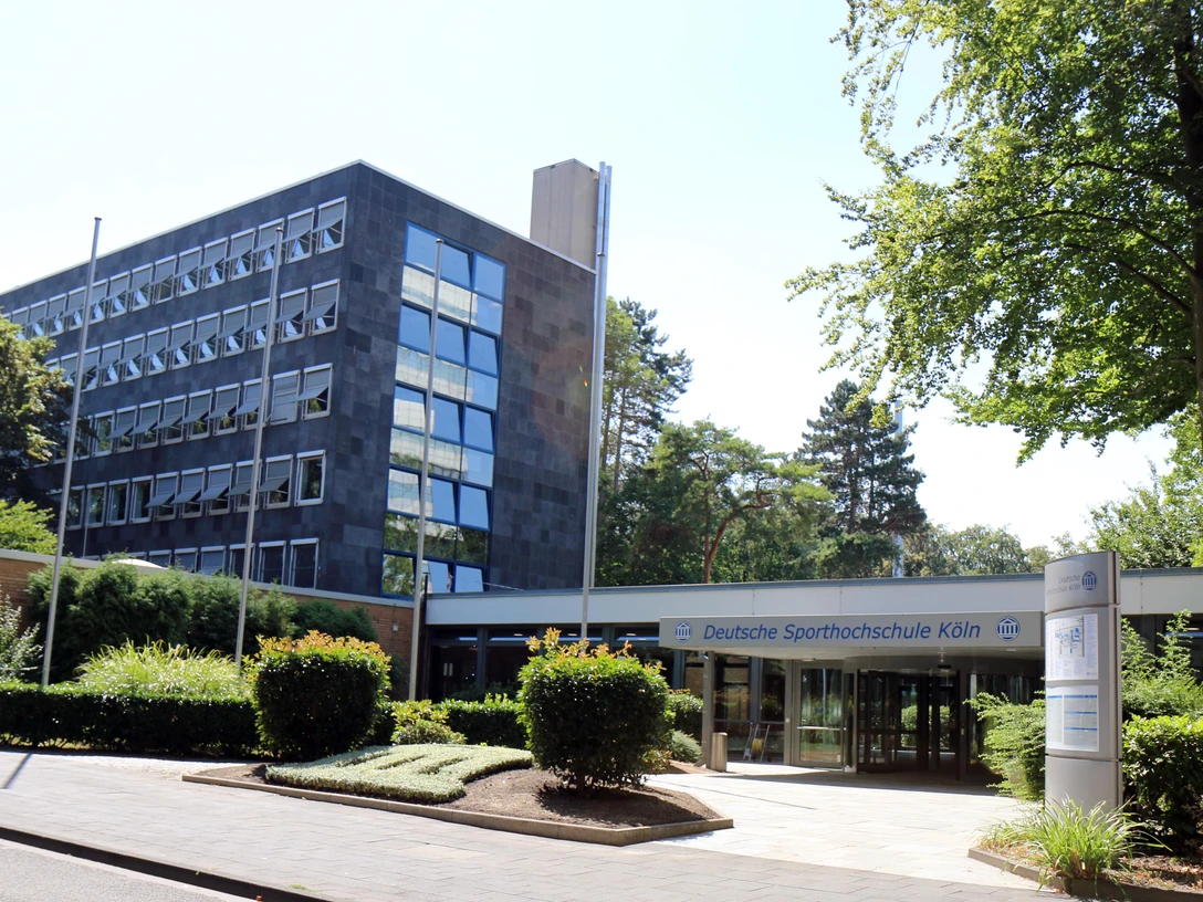 DSHS-Haupteingang Haupteingang der Deutschen Sporthochschule Köln mit Grünflächen und modernen Gebäuden.Main entrance of the German Sport University Cologne with green areas and modern buildings.