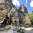 Tyssaer Wände Scogliere di arenaria con grotte e alberi sotto un cielo azzurro.