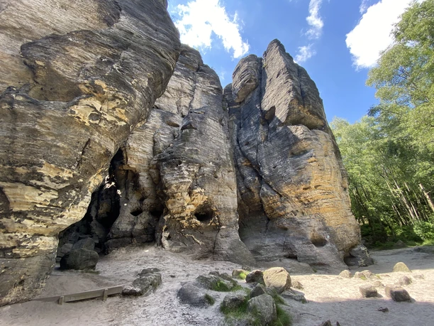 Tyssaer Wände Sandsteinfelsen mit Höhlen und Bäumen unter blauem Himmel.