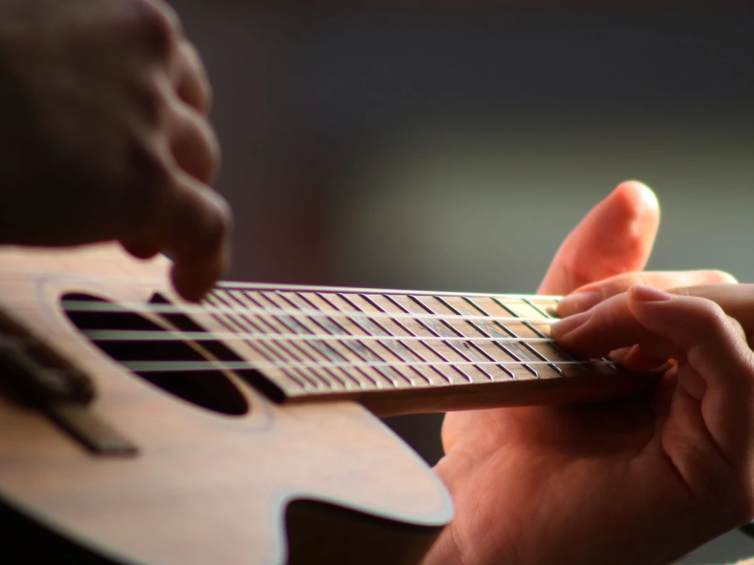 Ukulele Nahaufnahme einer Hand, die eine Ukulele spielt und über die Saiten greift.