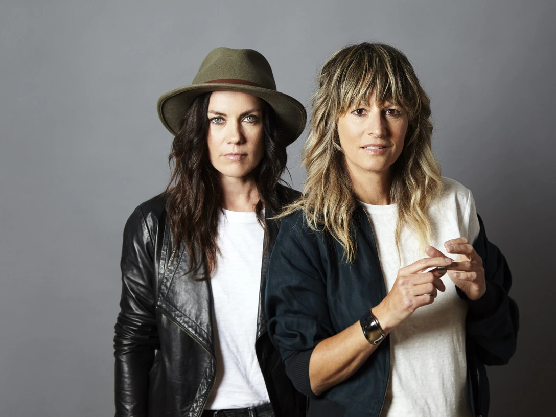 Madison Violet Zwei Frauen stehen nebeneinander vor grauem Hintergrund, blicken ruhig in die Kamera.