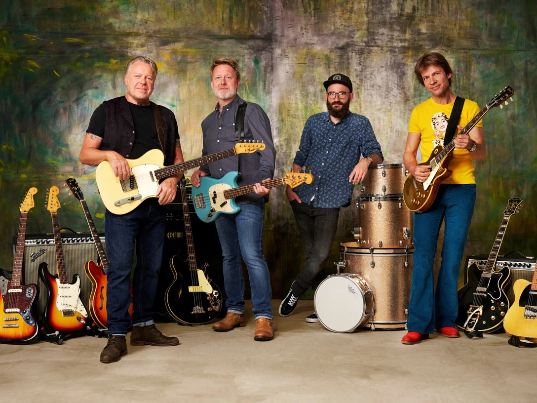 Richie Arndt Band feat. Gregor Hilden: GREEN-ish Vier Musiker mit E-Gitarren und Bass vor Verstärkern und Schlagzeug, lässig nebeneinander stehend.