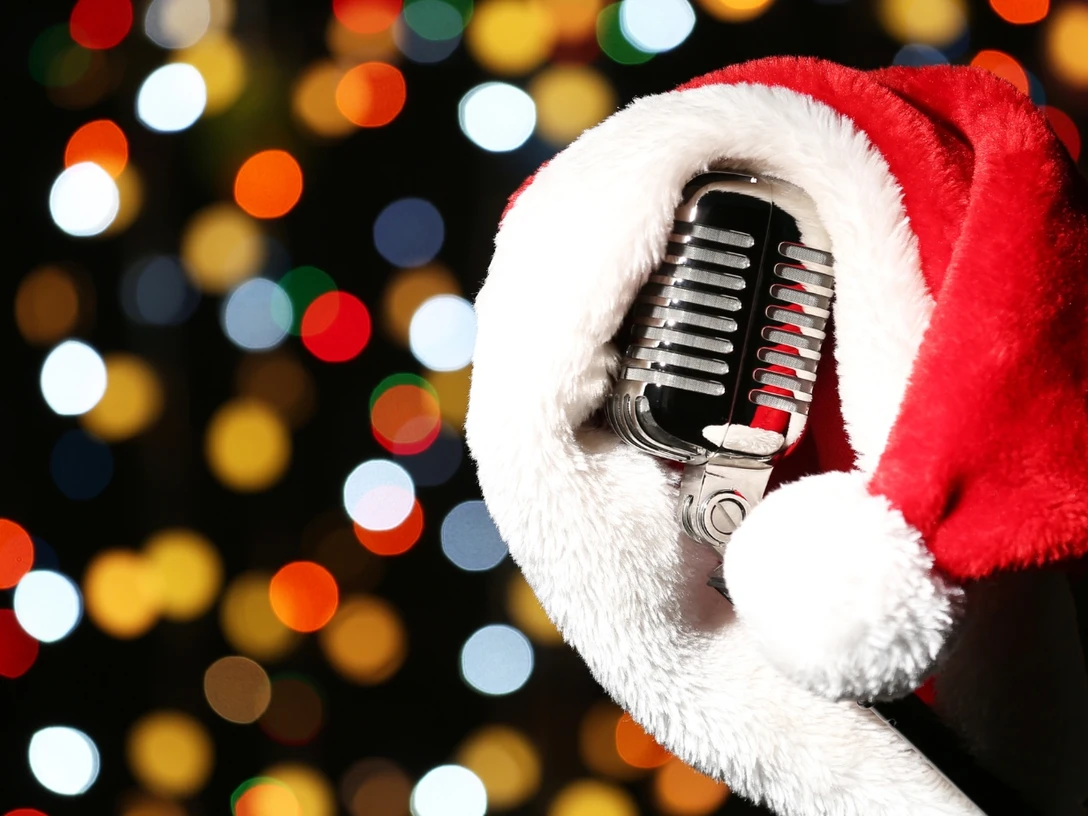 Nikolaus-Party Silbernes Retro-Mikrofon mit roter Weihnachtsmütze vor bunten, unscharfen Lichtern.