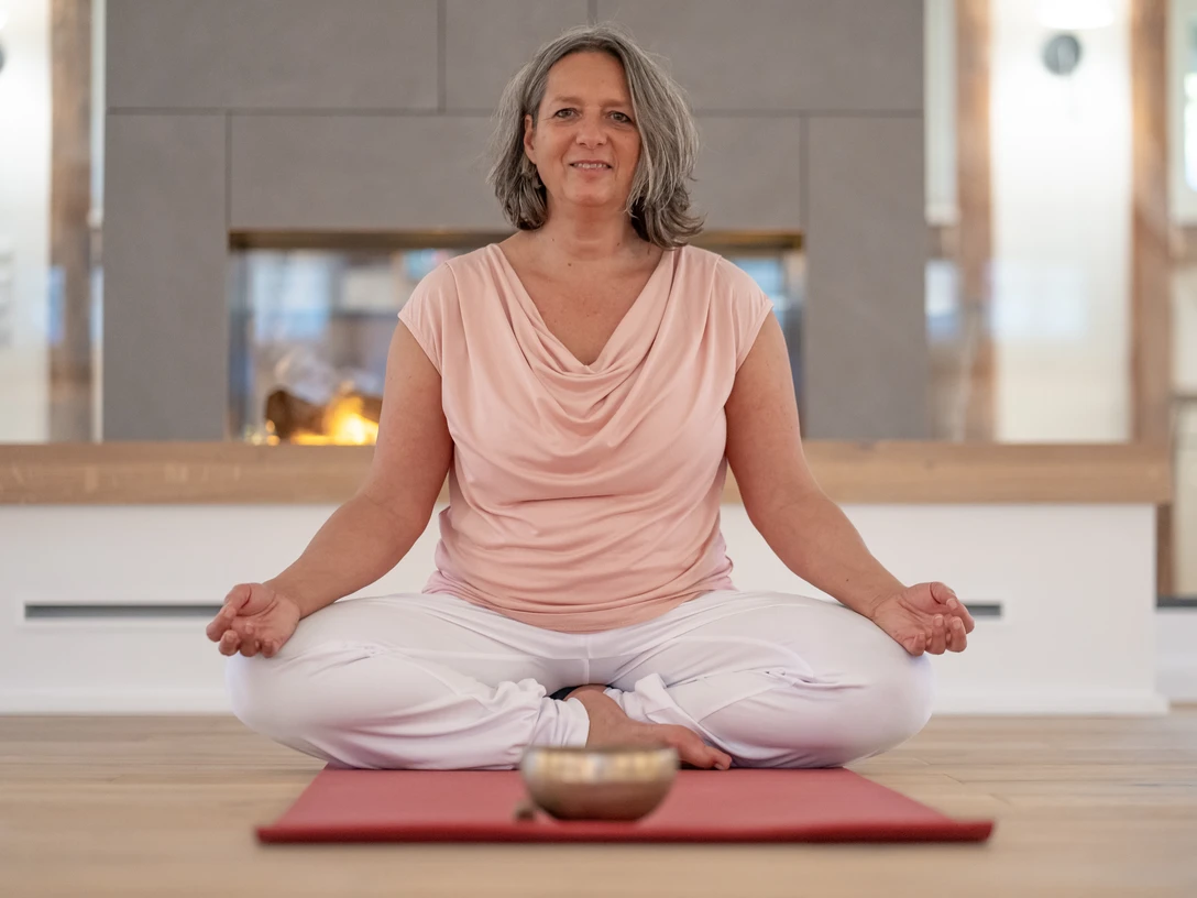 4 - DSC07588.jpg Frau sitzt entspannt im Schneidersitz auf einer Yogamatte vor einem Kamin und meditiert.Woman sits relaxed cross-legged on a yoga mat in front of a fireplace and meditates.Kvinde sidder afslappet med benene over kors på en yogamåtte foran en pejs og mediterer.Vrouw zit ontspannen in kleermakerszit op een yogamatje voor de open haard en mediteert.