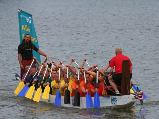 D.R.E.A.M. - Drachenboot-Tour - Besatzung Ein Drachenboot mit voller Besatzung fährt über das Wasser.