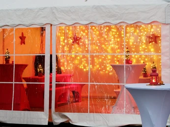 mSa Mobiler Weihnachtsmarkt Beheiztes Zelt mit Lichtervorhang und Stehtischen in Rot – gemütliche Loungezone auf dem mobilen Weihnachtsmarkt für die Firmenweihnachtsfeier.Heated tent with curtain of lights and bar tables in red - cozy lounge zone at the mobile Christmas market for the company Christmas party.