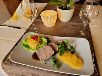 Elegante Essenspräsentation mit herzhaftem Braten, frischer Salatblattgarnierung und Orangen.