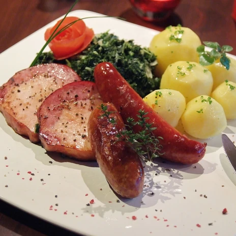 Grünkohl mit Kasseler und Kohlwurst – Essen im Emsland 06 ©Ute Müller (nordmedia).JPG Teller mit Grünkohl, Kasseler, Kohlwurst und Salzkartoffeln, garniert mit Kräutern und Tomatenrose