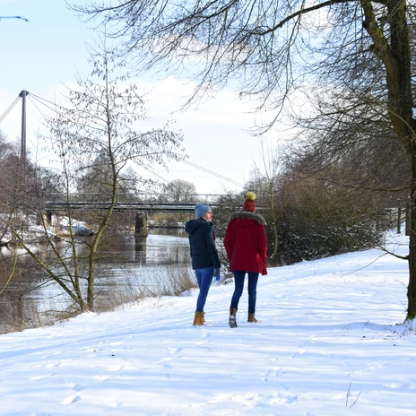 Winterspaziergang entlang Dortmund-Ems-Kanal und Koppelschleuse in Meppen ©Emsland Tourismus GmbH (30).jpg Zwei Personen spazieren im Winter entlang eines verschneiten Flussufers bei der Koppelschleuse Meppen.
