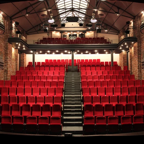 Theater auf der Werft, Papenburg – Zuschauerraum ©Papenburg Kultur.jpg Zuschauerraum mit roten Theatersitzen, umgeben von Backsteinwänden und modernen Emporen.