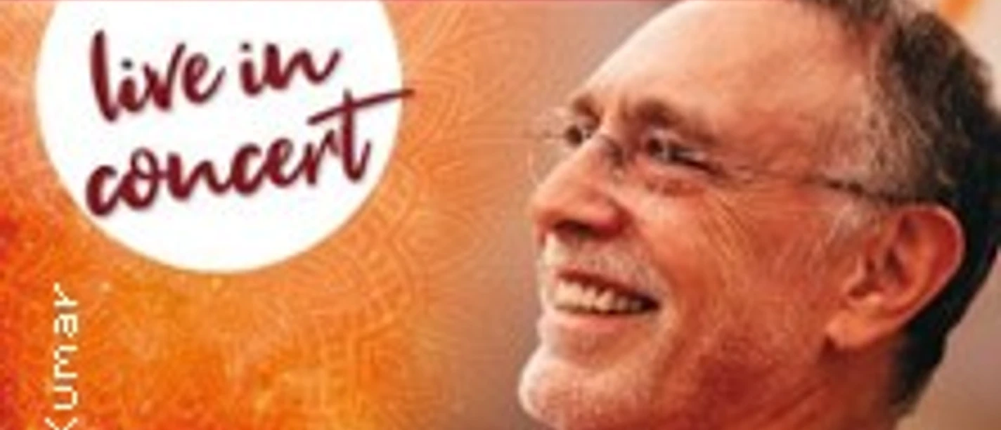 Krishna Das bei einem Live-Konzert, lächelnd bei der Ankündigung der "Home in the Heart Tour 2026".