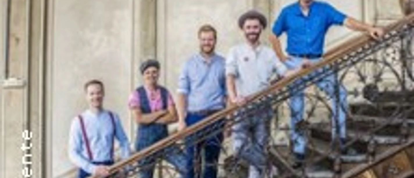 Fünf Personen posieren lächelnd auf einer alten, kunstvoll gestalteten Treppe.