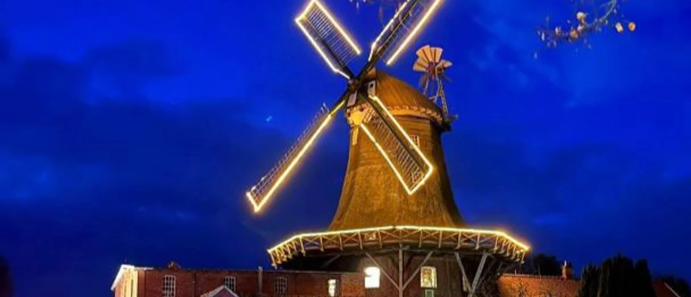 Mühle Pewsum Anleuchtfest Hell erleuchtete Windmühle in Pewsum bei Nacht mit bunten Lichteffekten am Gebäude.