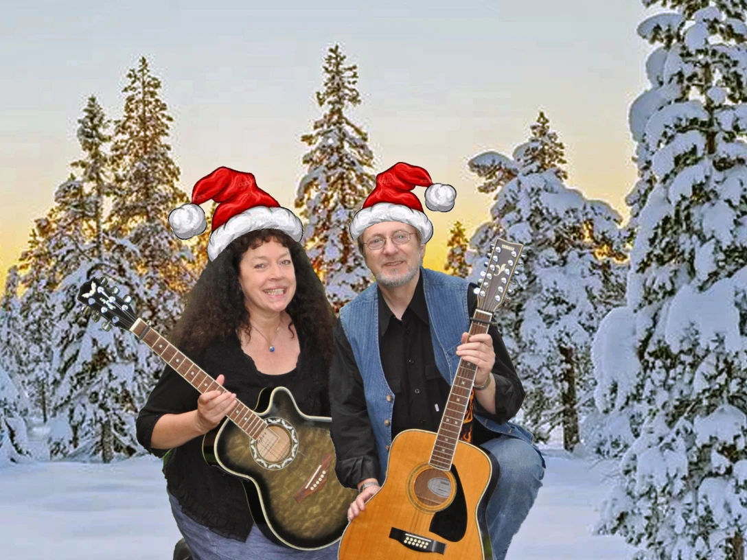 Dreebladd.png Zwei Personen knien im Schnee vor verschneiten Tannen, tragen Weihnachtsmützen und halten jeweils eine Gitarre.