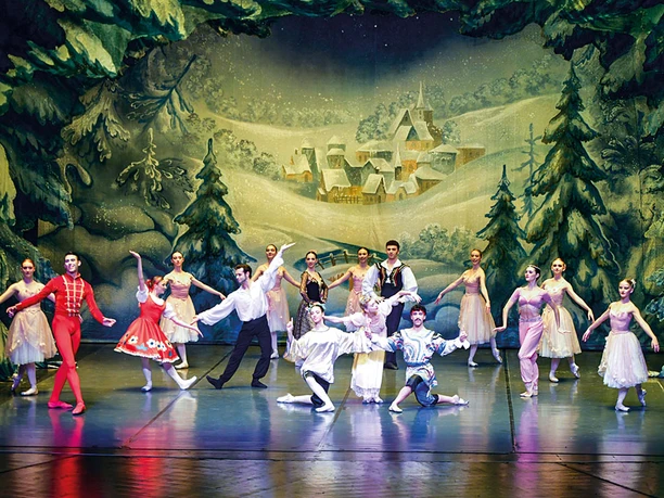 A ballet performance of "The Nutcracker" with dancers on a wintery stage.