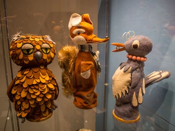 9 - Sandmännchen in Leipzig - Foto Andreas Schmidt.jpg Puppenfiguren von Fuchs, Eule und Vogel aus der Serie "Sandmännchen" in einer Vitrine.Puppet figures of a fox, owl and bird from the "Sandman" series in a display case.Loutkové figurky lišky, sovy a ptáka ze série "Sandman" ve vitríně.Figurki lisa, sowy i ptaka z serii "Sandman" w gablocie.Poppenfiguren van vos, uil en vogel uit de serie "Sandman" in een vitrinekast.Figure di volpe, gufo e uccello della serie "Sandman" in una vetrina.
