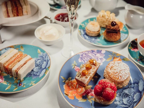 Afternoon Tea Eine Auswahl an kunstvoll arrangierten, feinen Teesandwiches und Gebäck auf einem gedeckten Tisch.