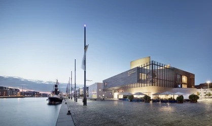Deutsches Auswandererhaus Ensemble Hafenansicht 1 (c) Werner Huthmacher_Deutsches Auswandererhaus.jpg Moderne Museumsarchitektur am beleuchteten Hafenbecken mit Schiffen im Abendlicht von Bremerhaven.