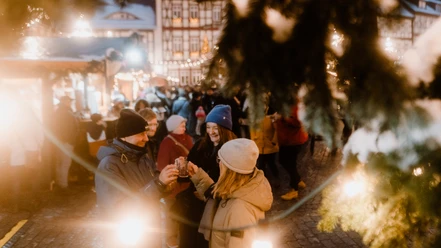 Weihnachtsmarkt Menschen stoßen mit Glühwein auf dem beleuchteten Weihnachtsmarkt in Wernigerode an.