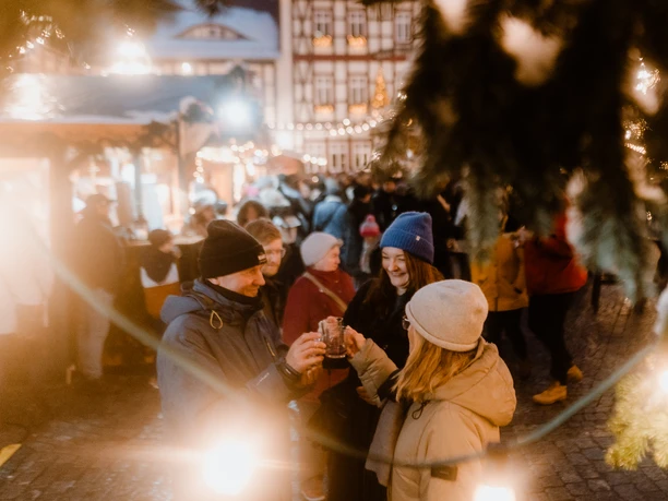 Weihnachtsmarkt Menschen stoßen mit Glühwein auf dem beleuchteten Weihnachtsmarkt in Wernigerode an.