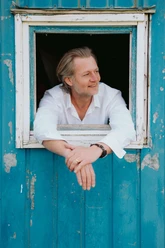 Christian-Maier-Schokoladenseitn.jpg Christian Maier im weißen Hemd lehnt aus einem blauen Fenster.