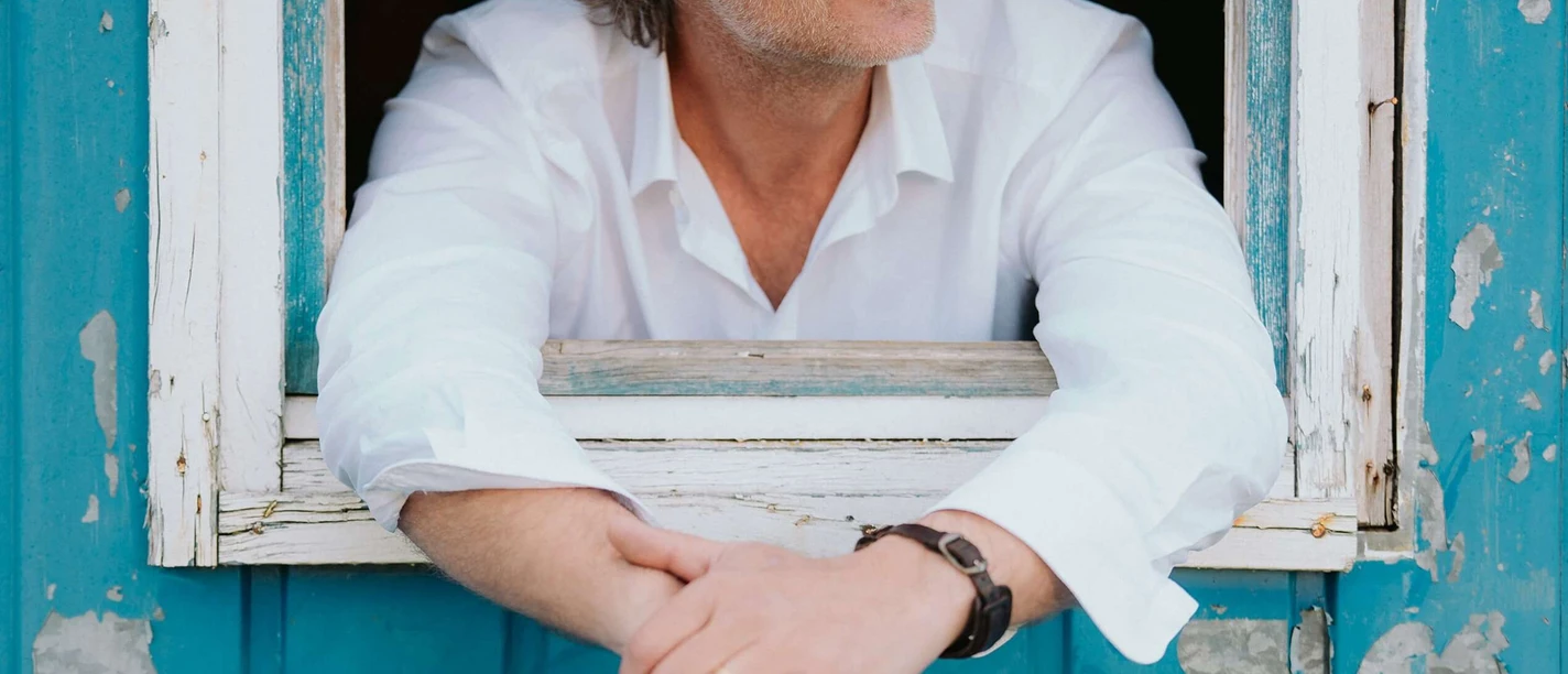 Christian-Maier-Schokoladenseitn.jpg Christian Maier im weißen Hemd lehnt aus einem blauen Fenster.