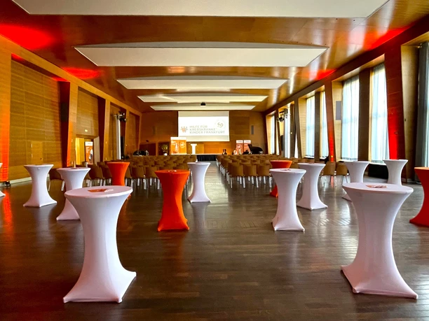 Campus Westend der Goethe-Universität - Festsaal Saal für Event mit Stehtischen, Stühlen, Bühne und rotem Licht.