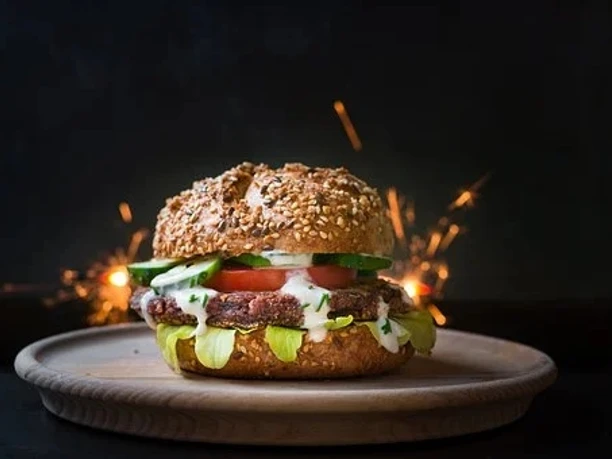 BurgerCompetition - Burger Burger auf Holzteller mit Belag und Wunderkerzen.