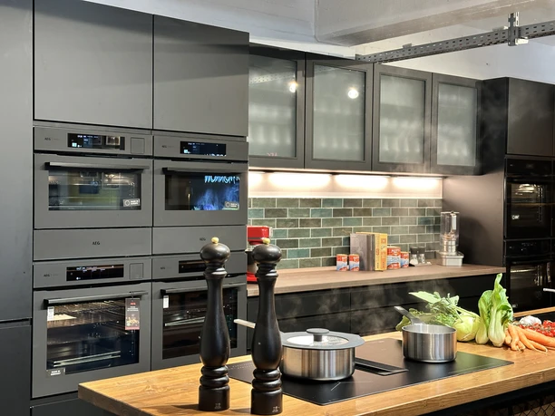 IMG_8826.jpg Modern kitchen with black appliances, wooden counters and fresh vegetables on the worktop.