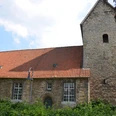 Kniestedter Kirche (10)_HD.JPG Kniestedter Kirche als Steinkirche mit rotem Ziegeldach und Turm, umgeben von Bäumen unter blauem Himmel.