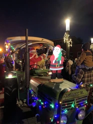 IMG_1022.JPG Ein festlich geschmückter Oldtimertraktor mit leuchtenden Lichterketten und verkleideter Nikolausfigur.