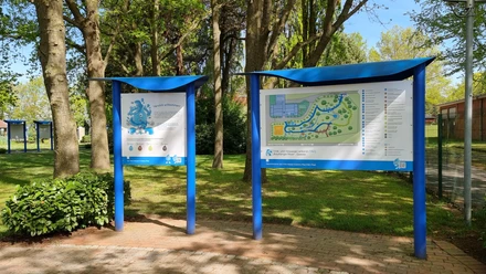 Trink-Wasser-Erlebnis-Pfad Geeste 2.jpg Infotafeln mit Lageplan und Begrüßung am Trink-Wasser-Erlebnis-Pfad in Geeste unter Bäumen.