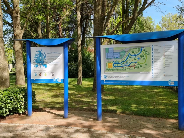 Trink-Wasser-Erlebnis-Pfad Geeste 2.jpg Infotafeln mit Lageplan und Begrüßung am Trink-Wasser-Erlebnis-Pfad in Geeste unter Bäumen.