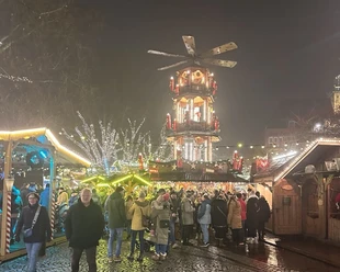 Mensen wandelen over de feestelijk verlichte Engelkemarkt in Emden met zijn grote kerstpiramide.