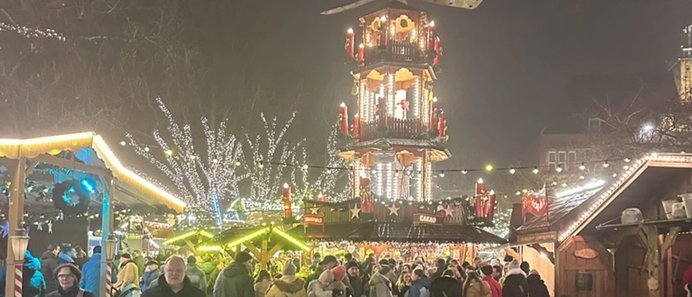 Martimer Engelkemarkt Emden.png Menschen bummeln über den festlich beleuchteten Engelkemarkt in Emden mit großer Weihnachtspyramide.
