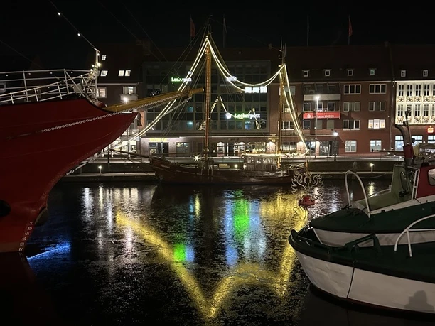 Beleuchtetes Schiff im Ratsdelft mit Lichterspiegelungen auf dem Wasser.