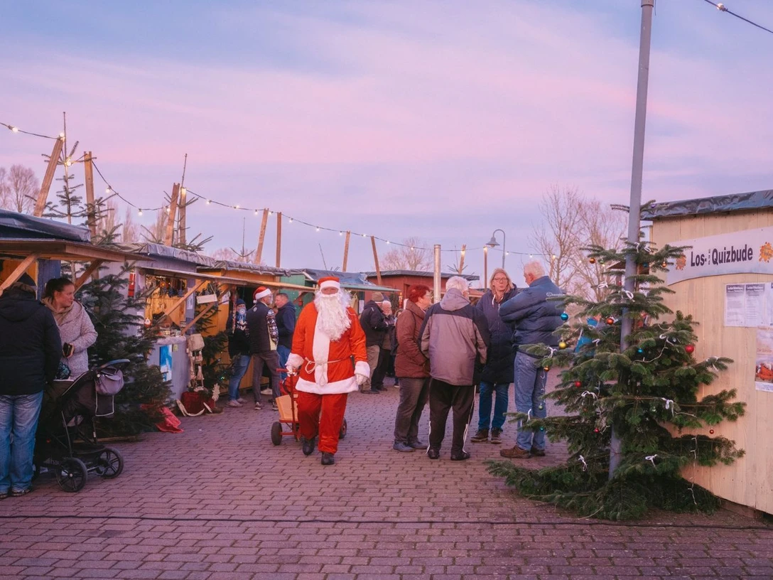 Weihnachtsmarkt Neuhaus an der Oste Weihnachtsmarkt mit festlich geschmückten Buden, Besuchern und Weihnachtsmann im Abendlicht