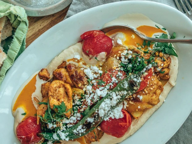 Kosmopolitische Küche im NENI Köln Ein köstliches NENI-Tellergericht mit gegrilltem Gemüse und frischen Kräutern.