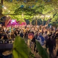 20 Jahre KuK 3 (c) Elke Kohlrautz.jpg Menschenmenge bei einem abendlichen Open-Air-Konzert, umgeben von Bäumen und Lichterketten.