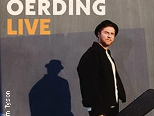 Johannes Oerding in schwarzer Kleidung vor grauer Wand mit Schattenprojektion.