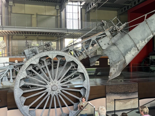 Annett Meiners erklärt den Mammut-Pflug und informiert über das einstige Leben im Moor.JPEG Frau spricht vor Besuchergruppe über den historischen Mammut-Pflug im Museumsgebäude des Moores.