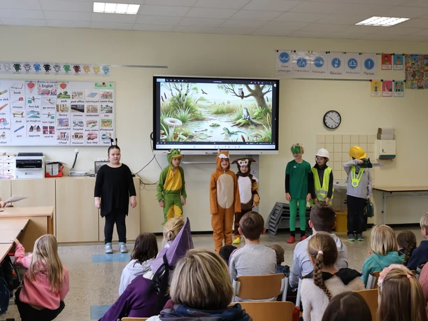 MOORex und das Moor der Wunder.JPG Kinder führen in einem Klassenraum ein Theaterstück mit Tier- und Entdeckerkostümen auf.