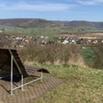 Ortsansicht von Amelunxen Von einer Liegebank aus genießt man den Ausblick auf das im Tal gelegene Amelunxen, im Hintergrund die Höhen des Weserberglands.